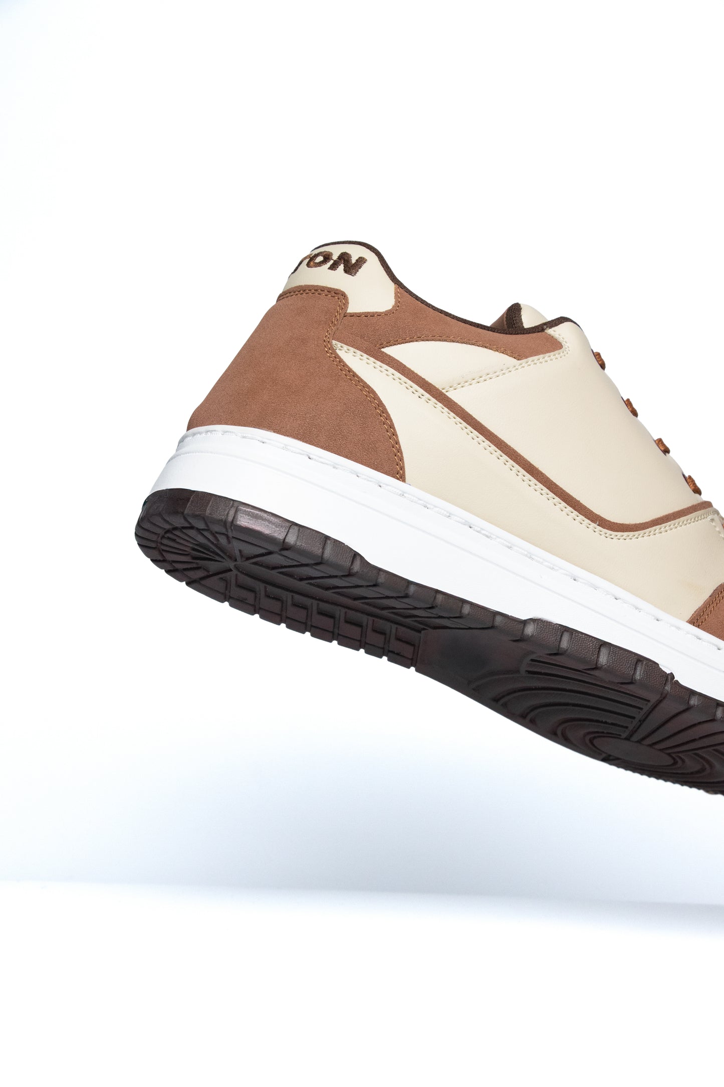Brown and beige sneaker with a white sole on a white background